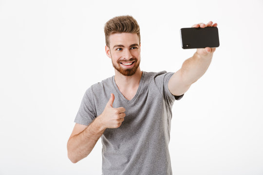Happy handsome young man make selfie by mobile phone with thumbs up gesture.