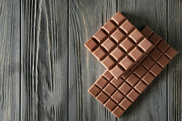 Tasty milk chocolate bars on wooden background