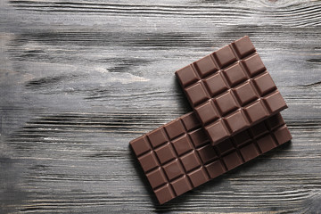 Tasty milk chocolate bars on wooden background