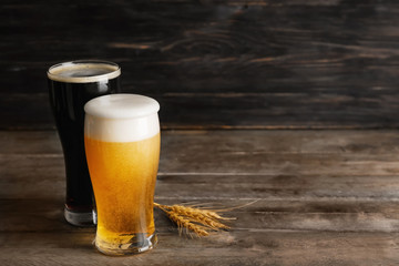 Glasses with cold beer and spikelets on wooden table