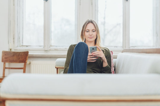Young woman relaxing on a sofa with a mobile