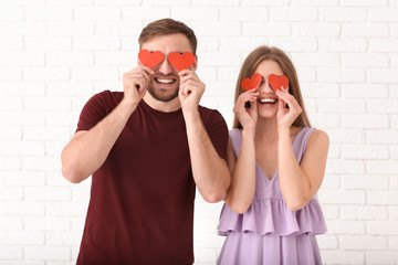 Happy young couple with red hearts on light background