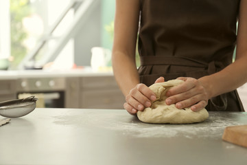 Woman kneading dough for bakery on kitchen table