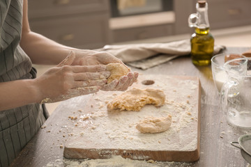 Woman making dough for bakery on table in kitchen