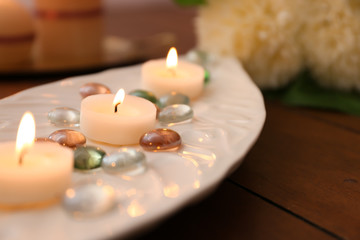 Obraz na płótnie Canvas Plate with burning wax candles on table, closeup