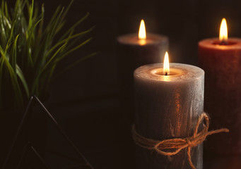 Burning wax candles on table in darkness