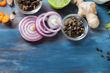 Various spices with sliced onion on wooden background