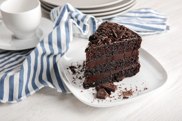 Plate with piece of delicious chocolate cake on wooden table