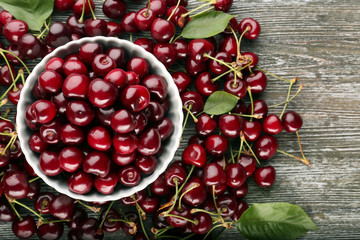 Bowl with tasty cherries on wooden table