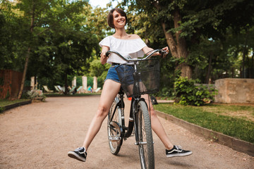 Happy young girl in summer clothes riding on a bicycle