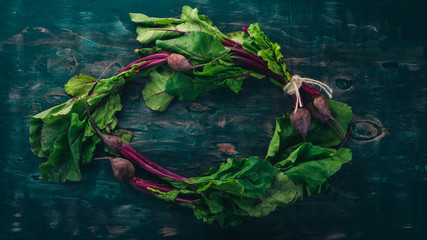 Fresh beetroot with green leaves. On a wooden background. Top view. Copy space.