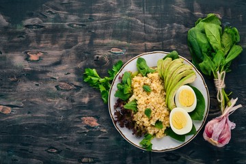 Bulgur with avocado, spinach and boiled egg. On a wooden background. Top view. Copy space.