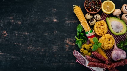 Concept of Italian cuisine. Pasta, Basil and Vegetables. On a wooden background. Top view. Copy space.