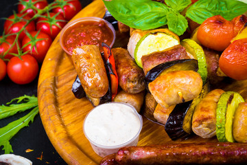 hot browned ruddy homemade sausages on a wooden tray with sauces and vegetables