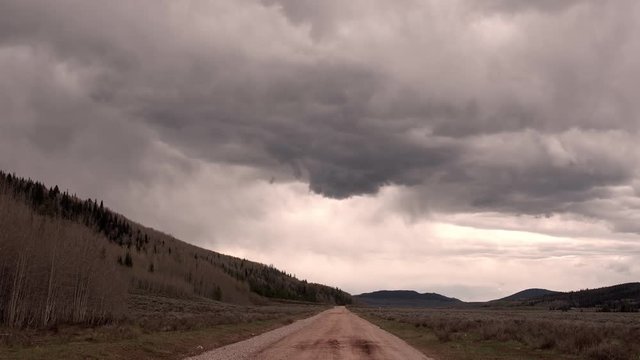 View of storm clouds building over dirt road in the Wyoming landscape.