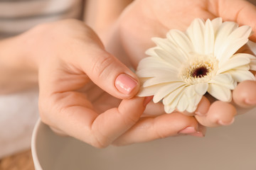 Obraz na płótnie Canvas Young woman with fresh manicure and beautiful flower after treatment in spa salon, closeup