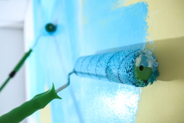 Painting wall with rollers indoors