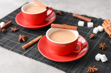Cups of aromatic tea with milk and spices on table