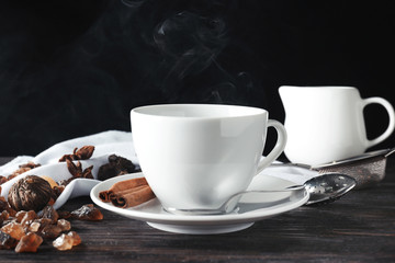 Cup with aromatic tea on table against dark background