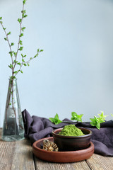 Bowl with powdered matcha green tea and whisk on wooden table