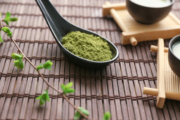 Spoon with powdered matcha green tea on bamboo mat