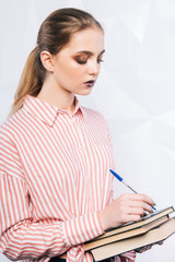 Portrait of a woman holding notebook with pencil over white background