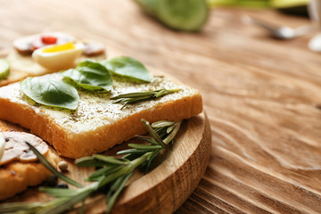 Different delicious toasts on wooden board, closeup