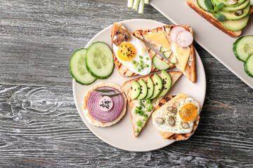 Plate with different delicious toasts on table
