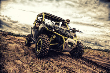 Mobile group of army rangers, state border guard service soldiers, armed commandos team moving and patrolling sandy territory on fast attack sandrail vehicle in twilight. Modern infantry light carrier