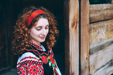 Young Slavonic woman in traditional embroidered costume sitting on the porch