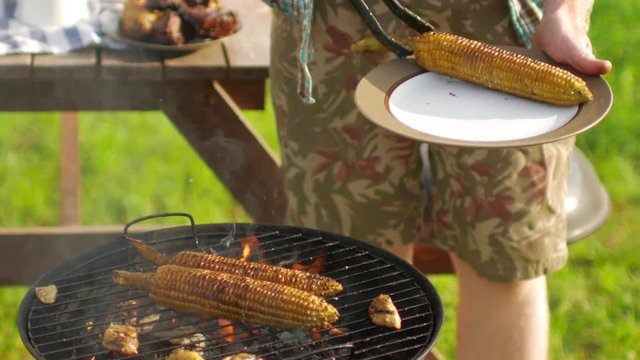 man cooking corn on the grill outdoors