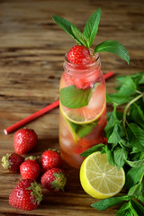 Lemonade with strawberry, lime, ice cubes and mint in a glass bottle