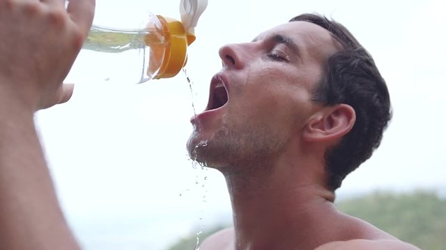 A male athlete quenches his thirst with water from a bottle. slow motion, 1920x1080, full hd