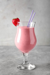 Glass with tasty strawberry smoothie on light table