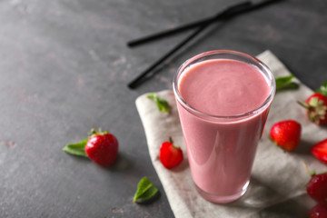 Glass with tasty strawberry smoothie on grey table