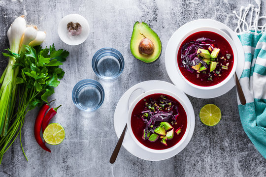Beetroot gazpacho soup with blue cabbage, avocado and green onions with lime juice on the table . healthy summer vegan food