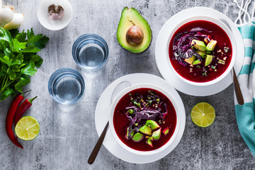 raw raw soup of fresh red vegetables and avocado in a plate on the table. healthy summer detox diet