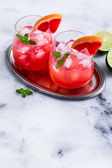 alcoholic cocktail Paloma of grapefruit and ice in glasses on a marble table . refreshing drink with lime juice