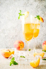 Summer cold alcohol beverage, iced peach Bellini cocktail with mint leaves, light concrete background copy space