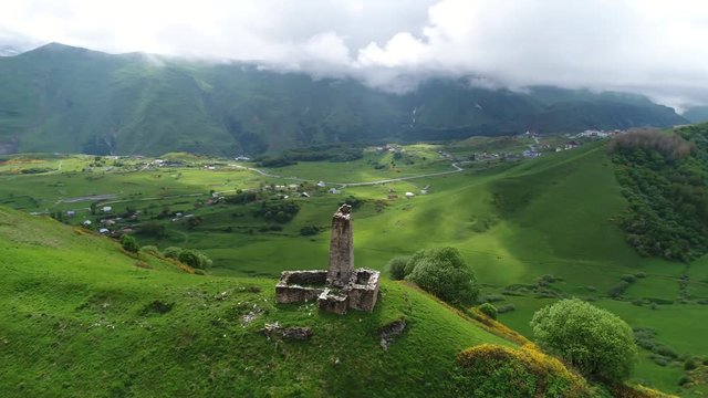 Flying around the old tower on a picturesque ridge among the high mountains. The ruins of the watchtower high in the mountains. Aerial view.