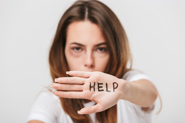 Disabled young girl with scratches and bruises showing stop gesture with help text on hand.