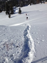 Some hikers advance in the snow on a sunny winter day in the mountains.