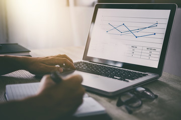Naklejka premium Professional at work, businessman writing report and using laptop working analysis investment connection at modern workplace