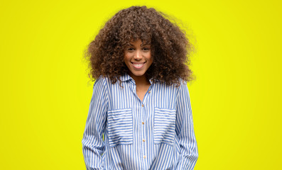 African american woman wearing a stripes shirt with a happy face standing and smiling with a confident smile showing teeth