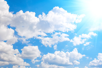 Naklejka na ściany i meble Blue sky with white summer cumulus clouds with sun ray shine glare.