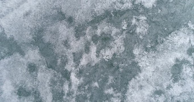 Drone rises above the frozen crystal ice of the lake Baikal. Top view. Natural background and patterns
