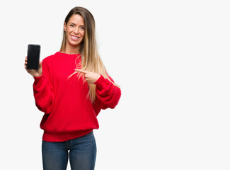Beautiful young woman using smartphone very happy pointing with hand and finger