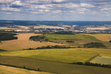 Landcsape with green sunny meadows and fields and town in the background from bird eye perspective