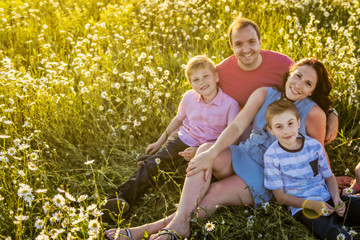 Happy family having fun on daisy field at sunset