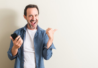 Senior man using smartphone pointing with hand and finger up with happy face smiling